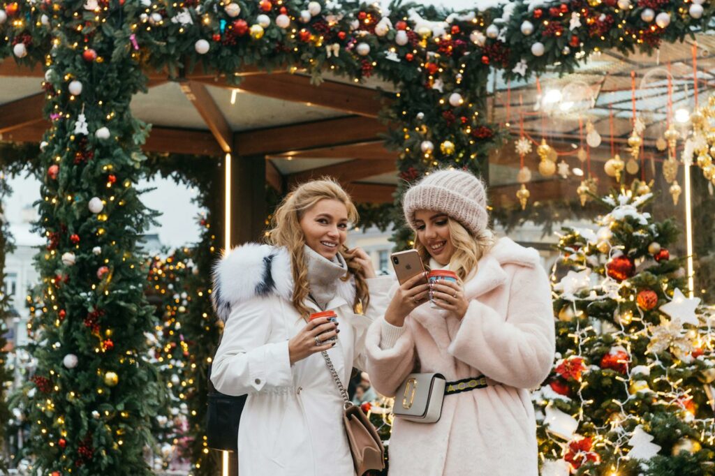 Women enjoying a festive Christmas market in Moscow, embracing winter vibes with warm drinks.