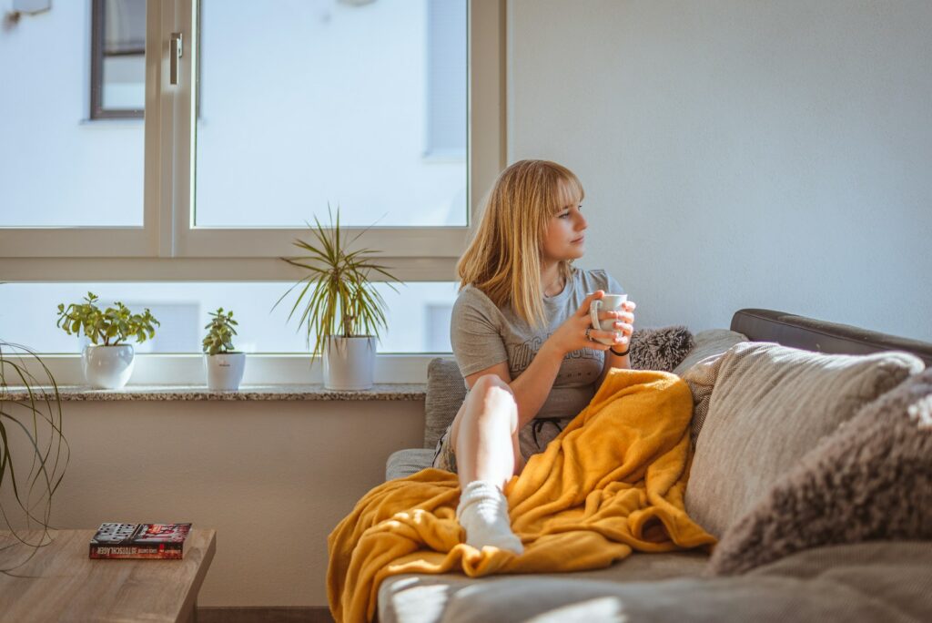 a woman sitting on a couch holding a glass of water